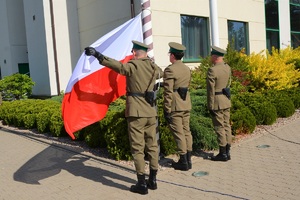 Funkcjonariusze NOSG wciągają na maszt flagę państwową