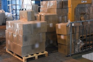 Funkcjonariusze prowadzą rozładunek towaru przewożonego tirem w celu ujawnienia przemycanych nielegalnych papierosów