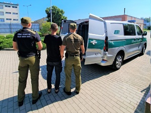 Funkcjonariusze SG doprowadzają do pojazdu służbowego osobę ztrzymaną