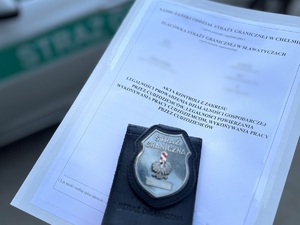 Odznaka służbowa funkcjonariusza SG na tle akt sprawy