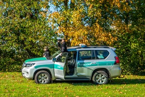 Funkcjonariusze SG podczas patrolu przy pojeździe słuzbowym