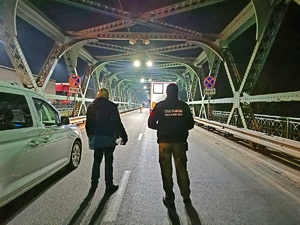 Funkcjonariusze SG podczas doprowadzenia osób zatrzymanych przy pojeździe służbowym