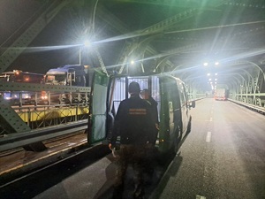 Funkcjonariusze SG podczas doprowadzenia osób zatrzymanych przy pojeździe służbowym