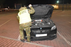 Funkcjonariusz Straży Granicznej prowadzi kontrolę graniczną pojazdu na terenie drogowego przejścia granicznego