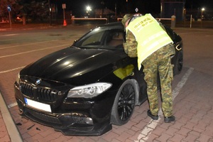 Funkcjonariusz Straży Granicznej prowadzi kontrolę graniczną pojazdu na terenie drogowego przejścia granicznego