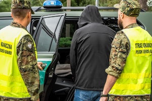 Funkcjonariusze SG podczas doprowadzania do pojazdu służbowego osoby zatrzymanej
